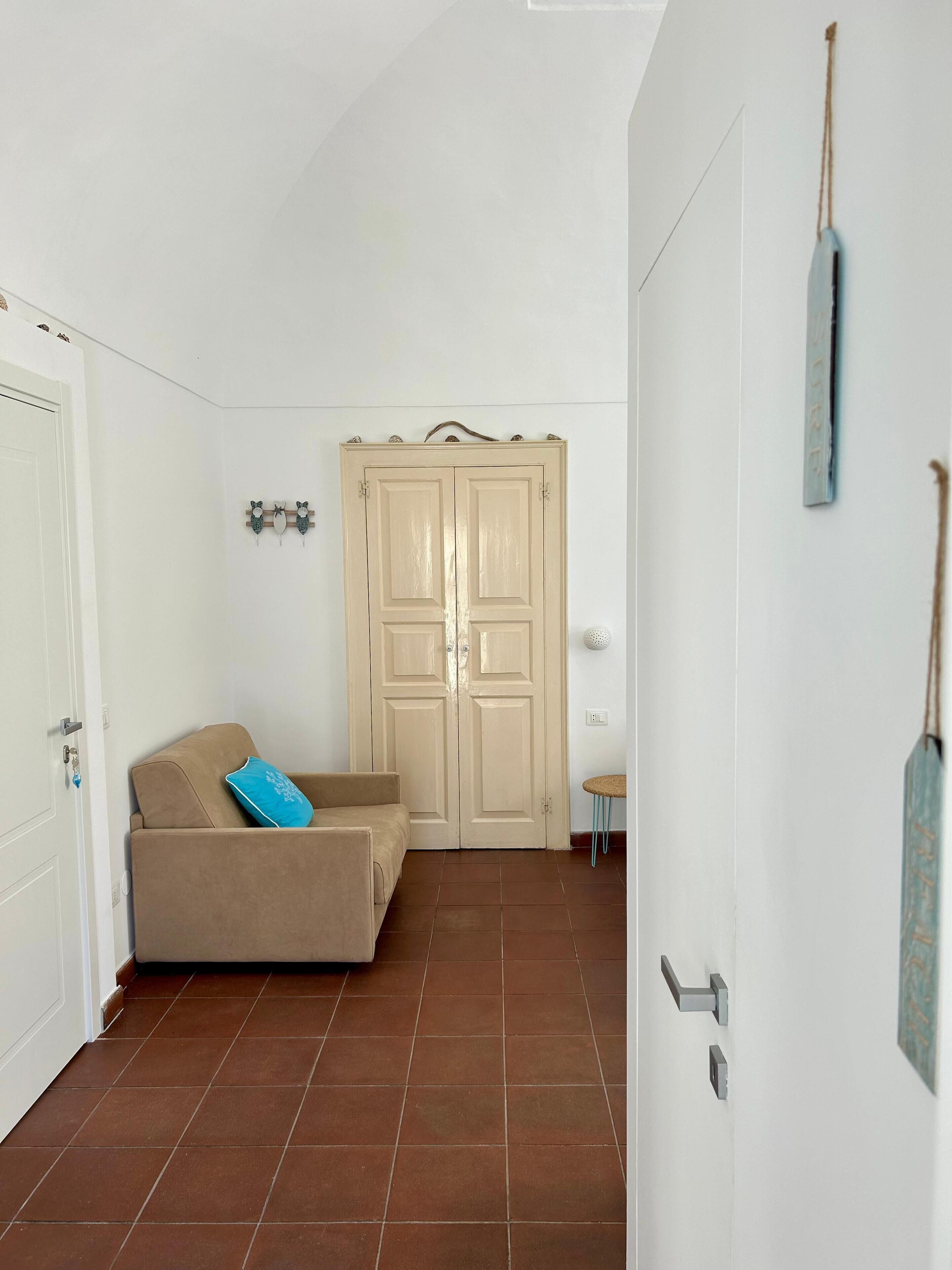 A room with a beige sofa, a wardrobe, and a small table.