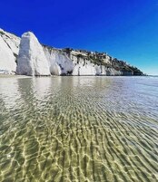 Una spiaggia ampia con scogliere bianche e acque calme.