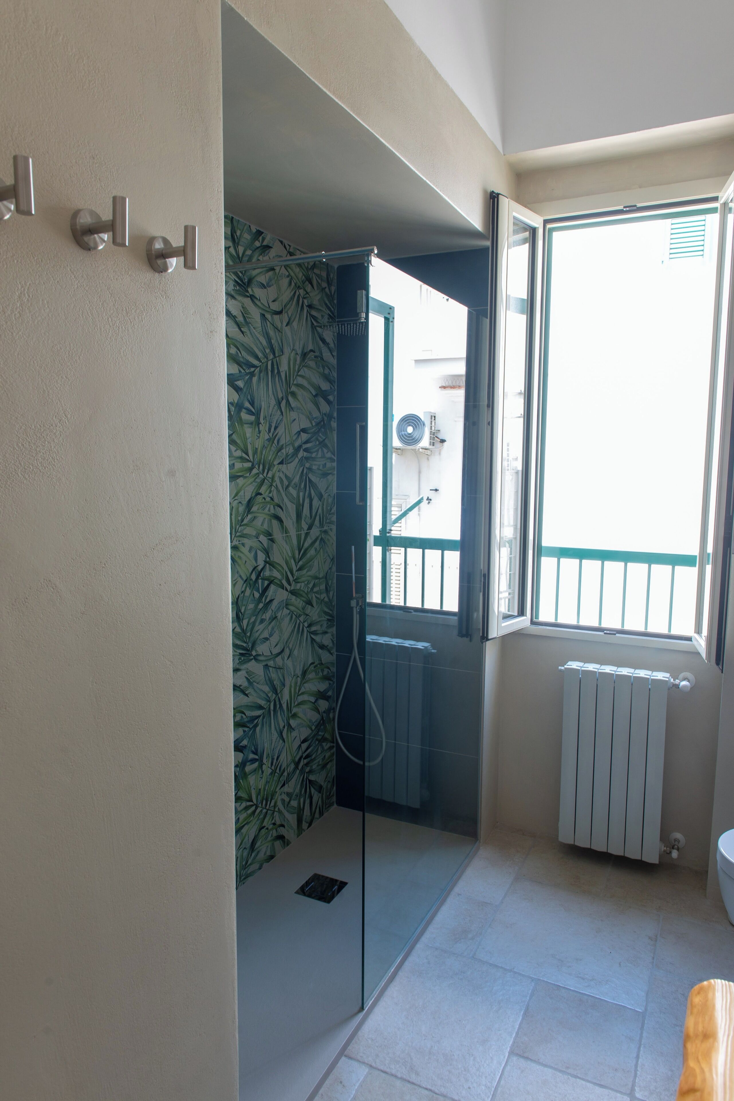 Une salle de bain équipée d’une douche, de toilettes, d’un radiateur et d’une fenêtre donnant sur l’extérieur.