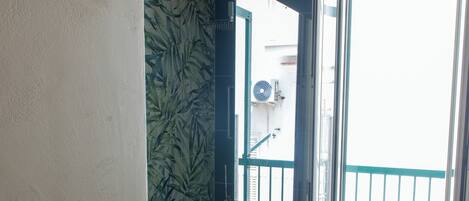 Un baño con ducha, inodoro, radiador y ventana con vistas al exterior.