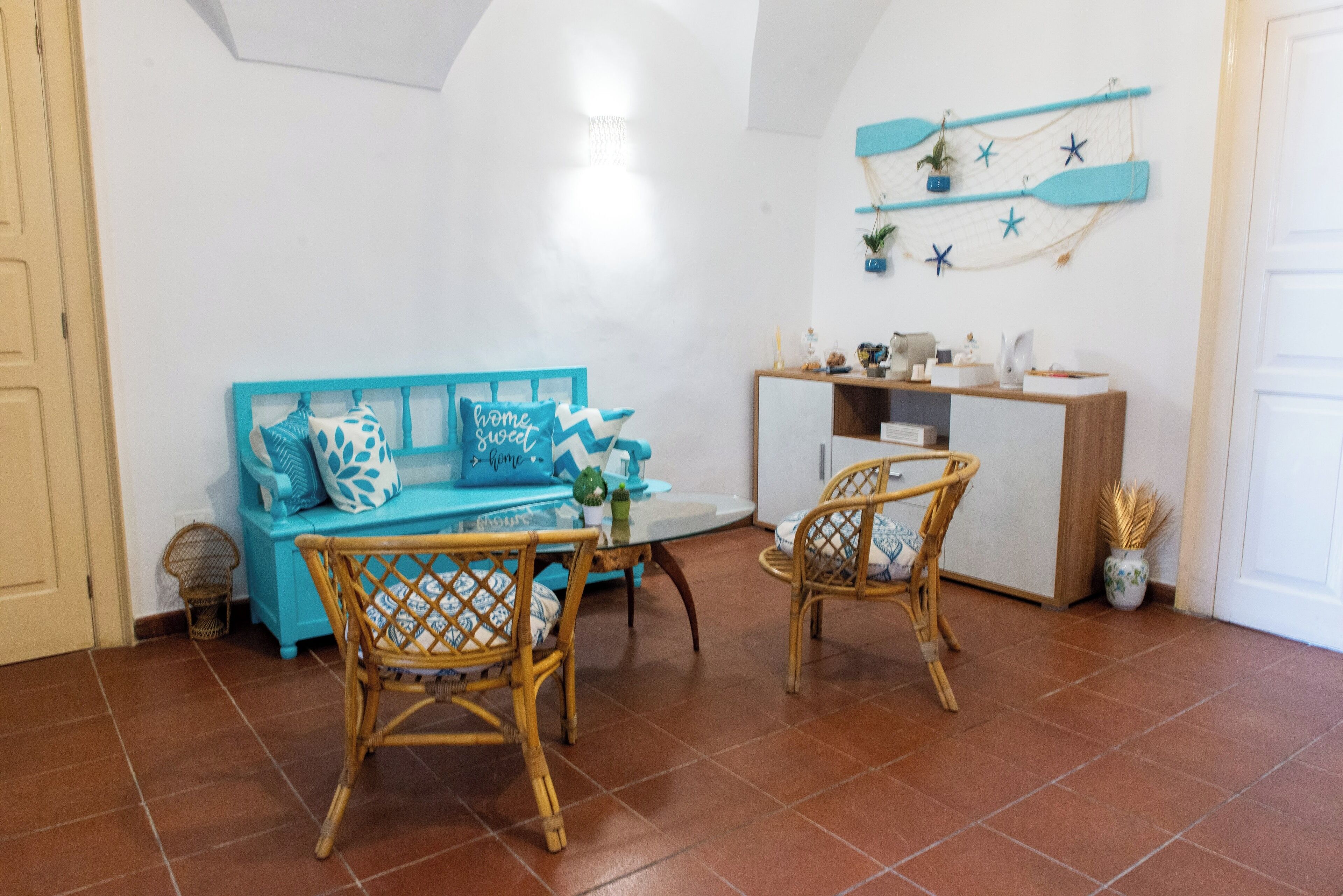 A cozy room with a blue sofa, wicker chairs, a small table, and a white cabinet.