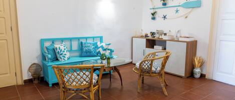 A cozy room with a blue sofa, wicker chairs, a small table, and a white cabinet.