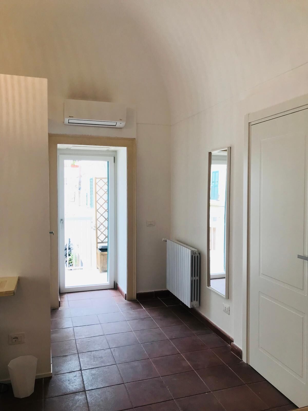 A hallway with a radiator, a door, and a window.
