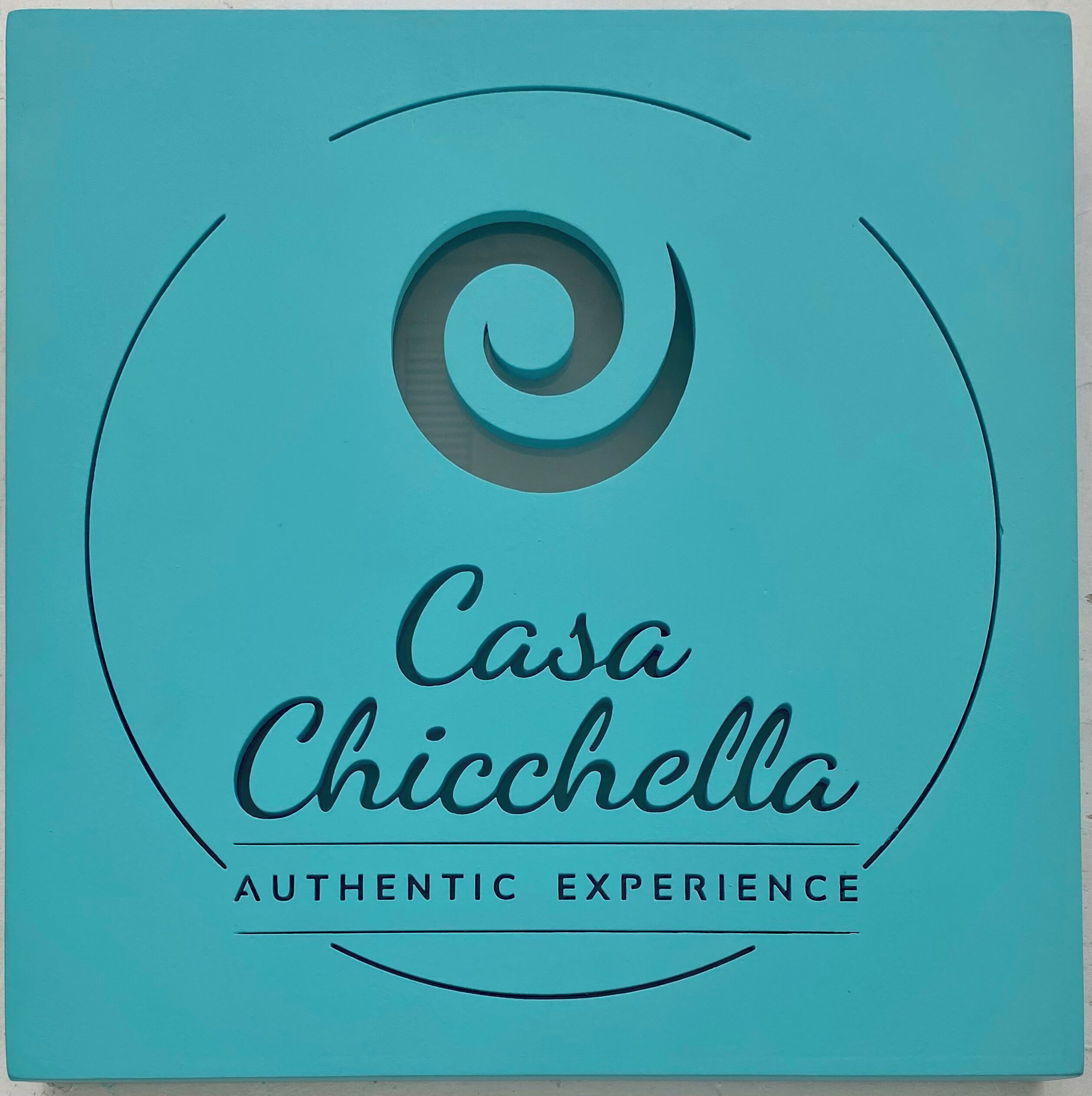 Ein Logo mit dem Text "Casa Chicchella" und "Authentisches Erlebnis" auf türkisem Hintergrund.