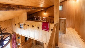 Ein Holzblockhaus-Interieur mit Schlafkoje, kleinem Tisch und Fenster.