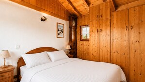 Ein Zimmer mit Holzboden, einem Bett, Nachttischen und einer Wanduhr.