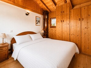 A wooden room with a bed, nightstands, and a wall clock. - Cozy chalet in village center, near slopes (Notre-Dame-de-Bellecombe)