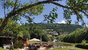 Ein Außenbereich mit Tischen und Stühlen, ein See und Gebäude im Hintergrund.