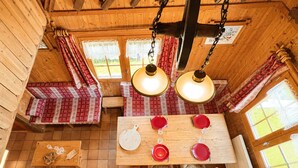 Ein rustikales Interieur mit einem Esstisch für vier Personen, Bänken und einer hängenden Leuchte.