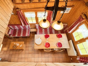 A wooden interior with a dining table set for four, benches, and a hanging light fixture. - Cozy chalet in village center, near slopes (Notre-Dame-de-Bellecombe)