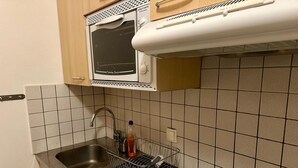 A compact kitchen with a microwave, double sink, and a stove. - Tignes: Apartment 6 pers, 41 sqm, Slope View (Tignes)