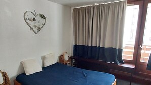 A bedroom with a wooden bed, a white wall, a heart-shaped decoration, and a window with curtains. - Tignes: Apartment 6 pers, 41 sqm, Slope View (Tignes)