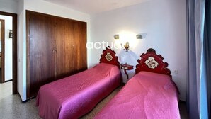 A room with two single beds, a wooden wardrobe, and a nightstand with a lamp. - Seafront apartment with terrace and parking in Platja d'Aro (Platja d'Aro)