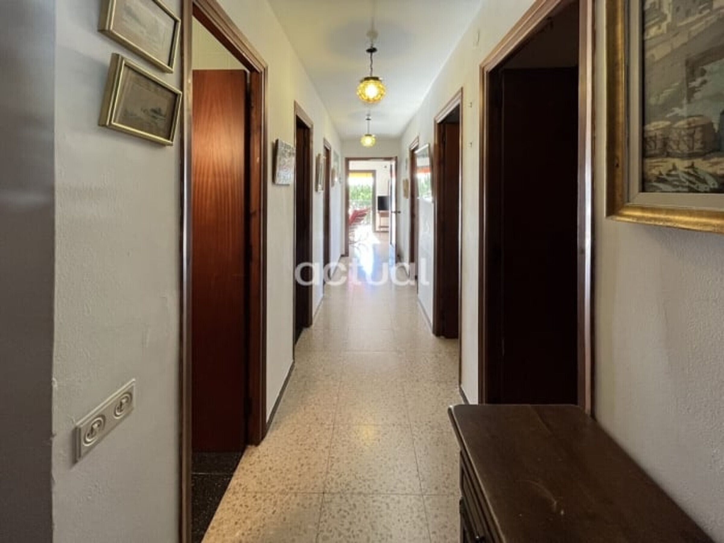 A hallway with wooden doors, a bench, and a light fixture.