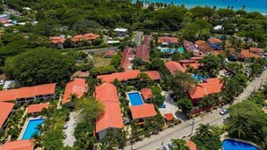 An aerial view of a resort with multiple buildings, swimming pools, and a beach. - Casa Rosa del Mar with beautiful views (Playas Del Coco)
