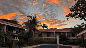 A hotel with a swimming pool, palm trees, and a sunset view. - Casa Rosa del Mar with beautiful views (Playas Del Coco)
