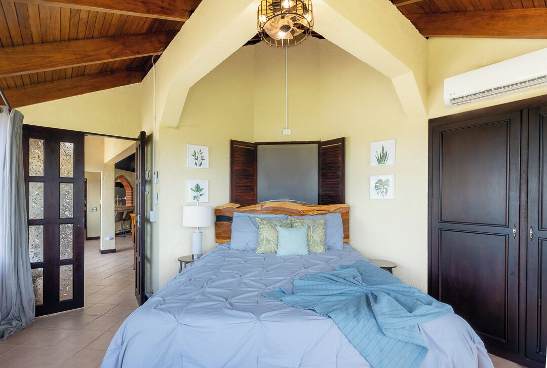 Ein Schlafzimmer mit einem großen Bett, einem Holzkopfende und einem Deckenventilator.