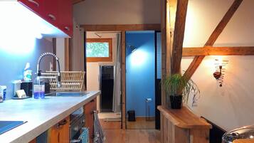Une cuisine avec un plancher en bois, un meuble rouge et un évier.