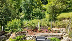 A garden with a stone wall, a wooden bench, and a small table.
