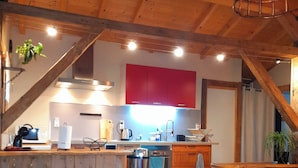 A rustic kitchen with wooden beams, a red cabinet, and a built-in oven.