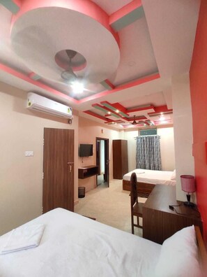 Una habitación de hotel con dos camas, un escritorio, un televisor y un ventilador de techo.