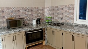 Una cocina con microondas, cafetera y horno pequeño.
