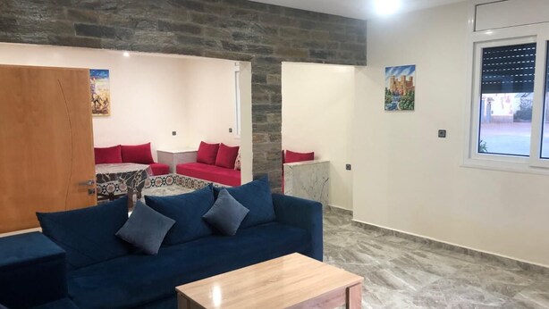 Una sala de estar con un sofá azul, una mesa de centro de madera y una pared de piedra.