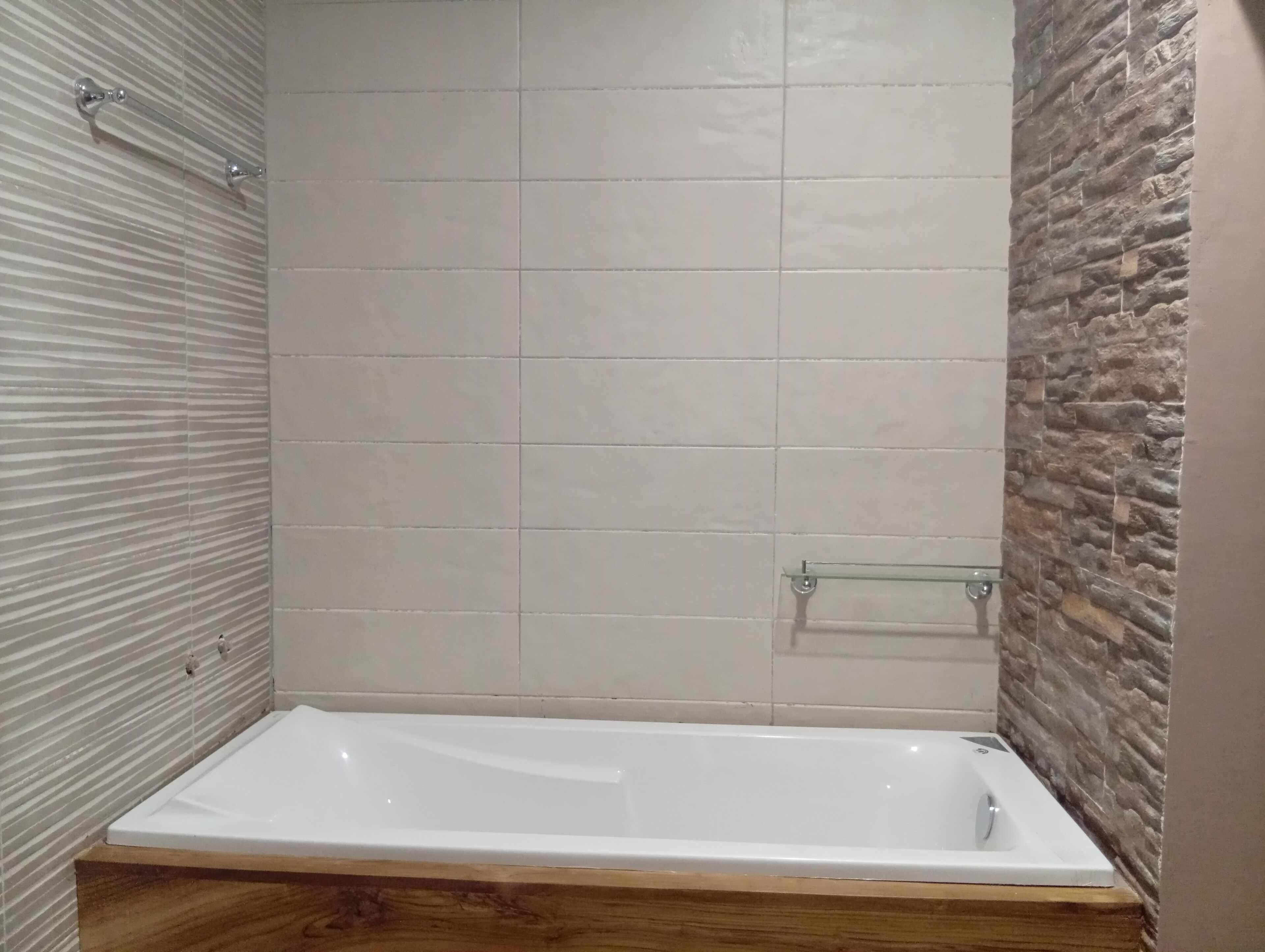 A modern bathroom with a rectangular bathtub, tiled walls, and a wooden vanity.