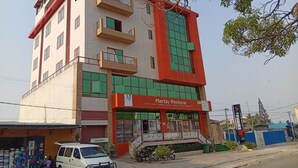 Un edificio de varios pisos con fachada roja y blanca, un letrero que dice 'Martin Patecar', y una camioneta blanca estacionada al frente.