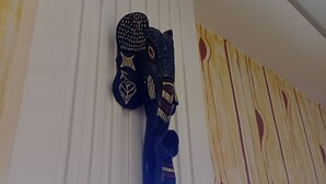 Un purificador de aire fijado a la pared y un adorno con forma de zapato sobre una pared blanca con líneas verticales.