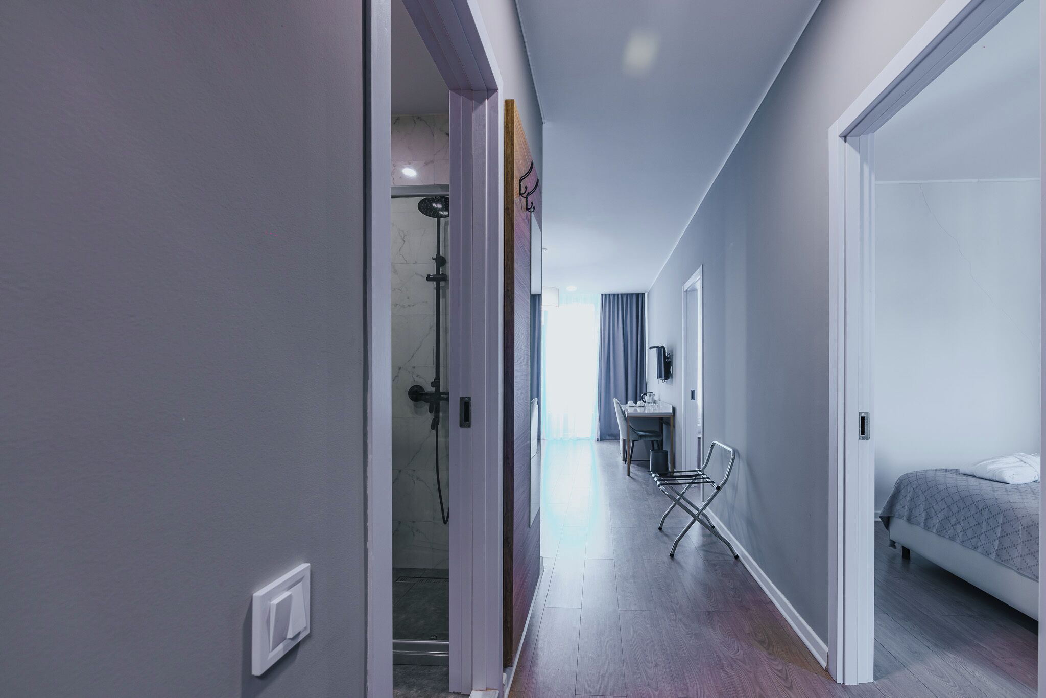 A modern hotel room with a bed, a desk, and a shower area.