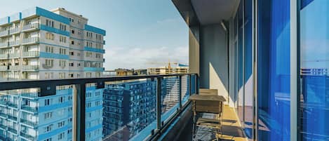 A modern apartment with a balcony, large windows, and a view of other buildings.