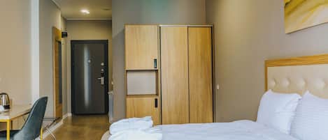 A hotel room with a bed, a desk, and a wardrobe.