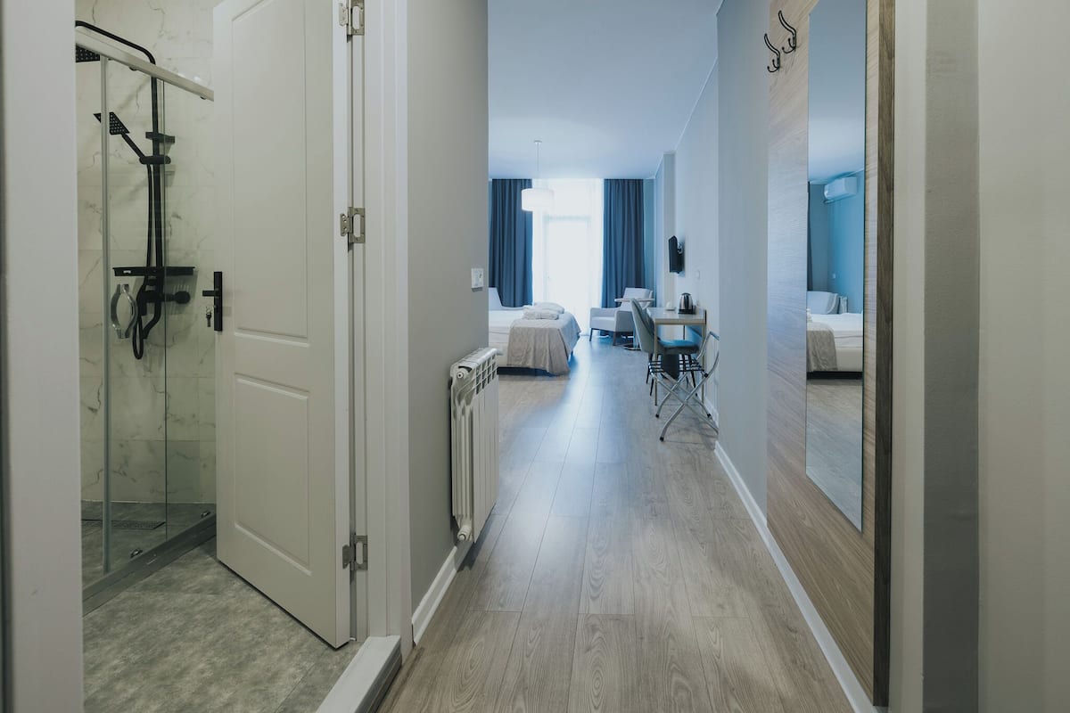 A hotel corridor with a shower, a bed, a desk, and a chair.