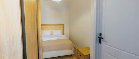 A bedroom with a bed, bedside table, and a hanging light fixture.