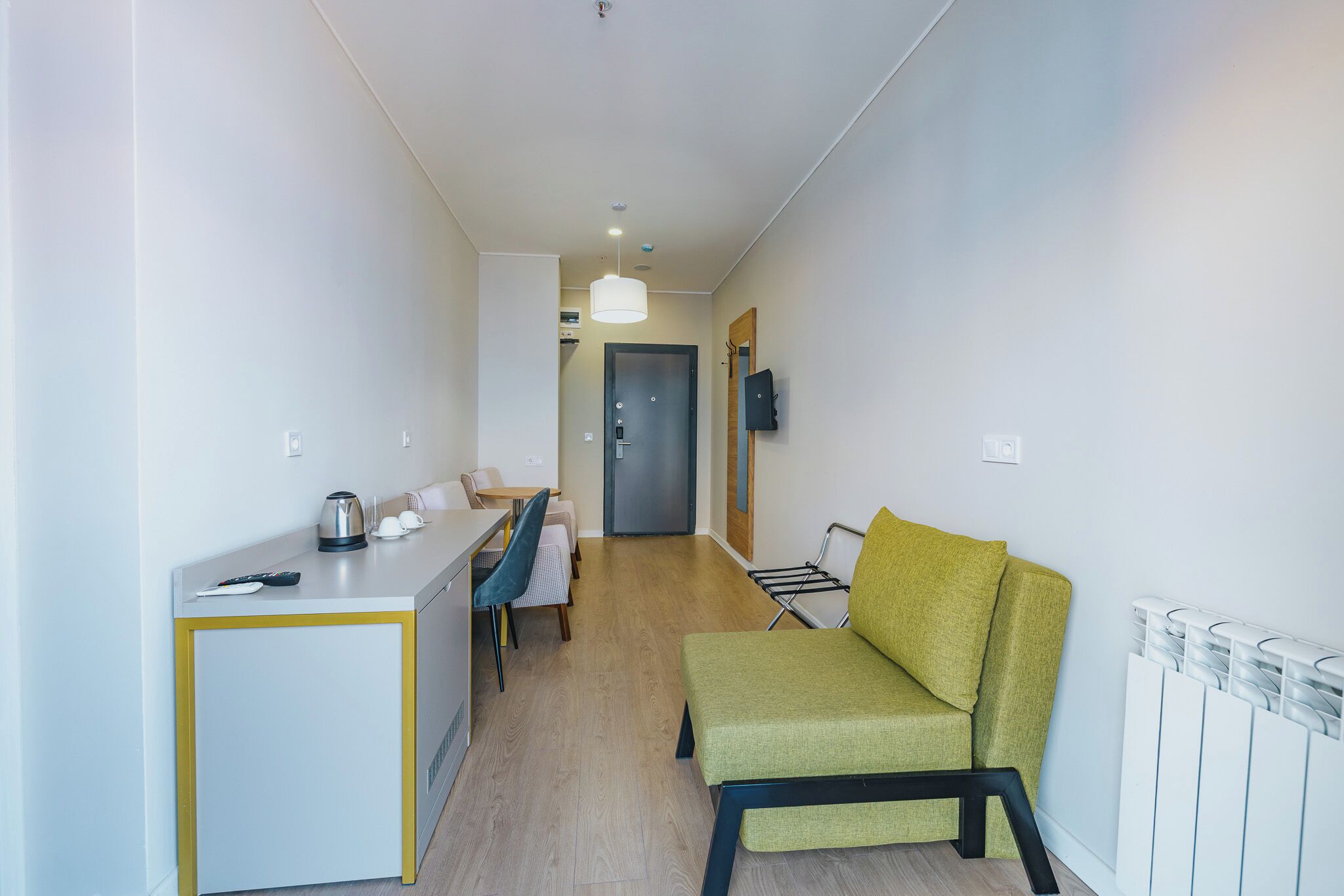 En kompakt bolig med et tekøkken, en sofa, et spiseområde og en gang, der fører til en dør.