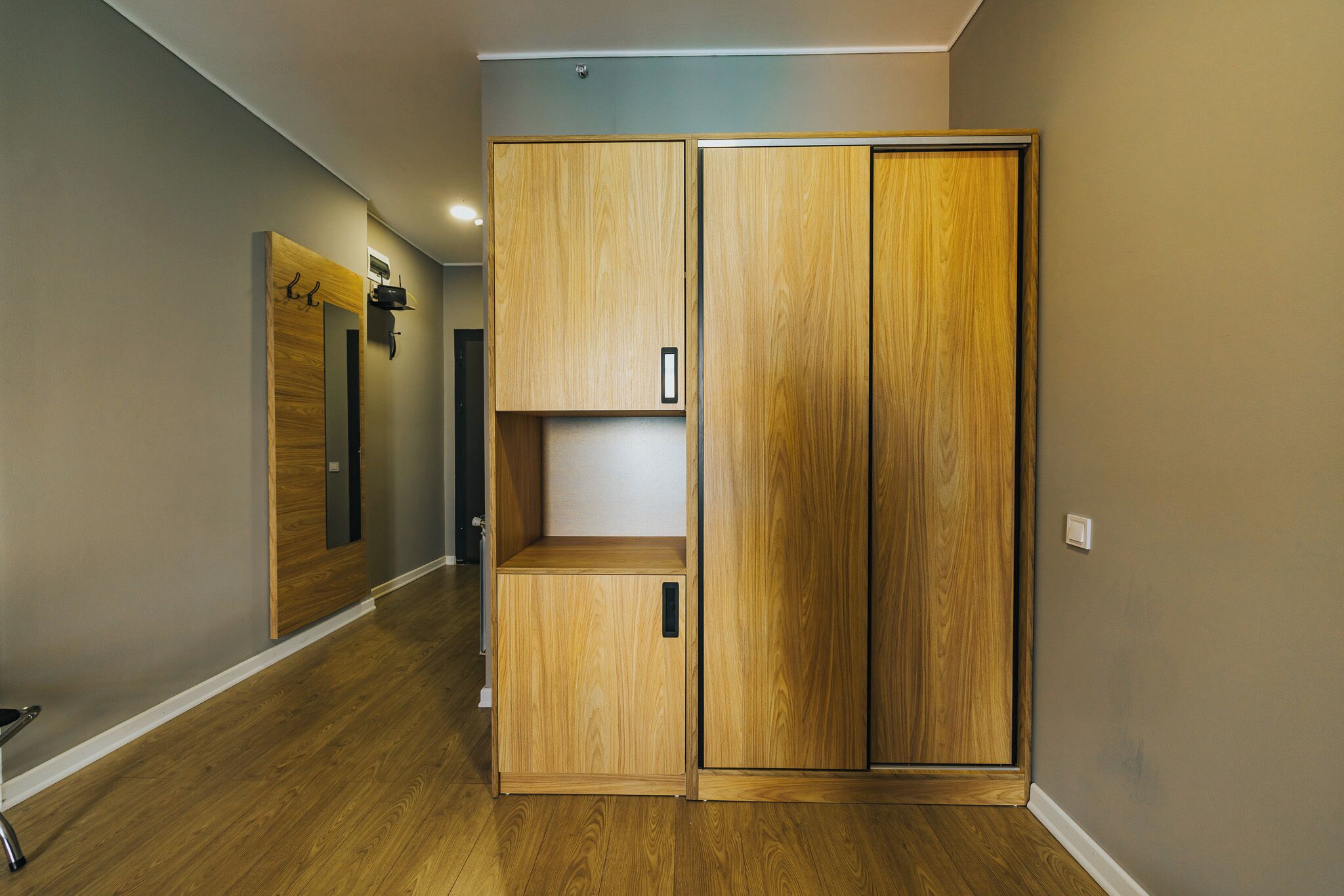 A hallway with wooden wardrobes and a mirror.