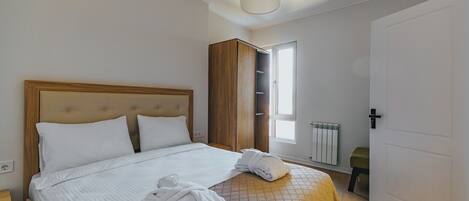 A neatly made bed with white linens, a wooden headboard, and a bedside table.