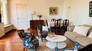A living room with a sofa, two armchairs, a coffee table, and a dining table with chairs. There is a door, a lamp, and a painting on the wall. - House of 100 m2 on 2 levels with garden of 1000 m2 center Cannes (Cannes)
