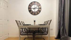 A dining area with a white table, black chairs, and a wall clock.