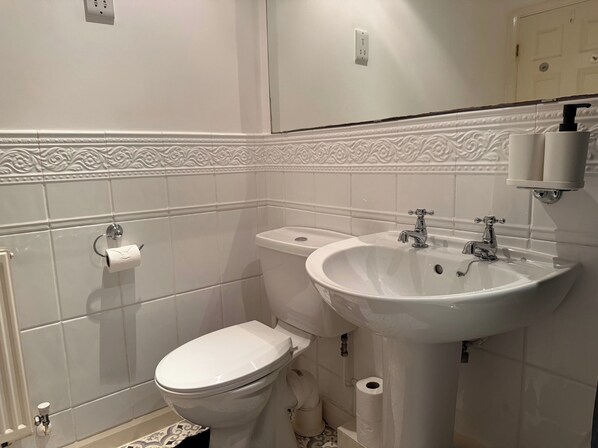 A bathroom with a toilet, sink, and a mirror.