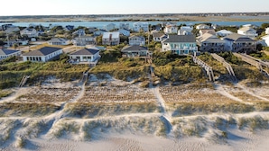 An aerial view of a coastal residential area with houses, sandy terrain, and a body of water in the background. - Oceanfront 5-bedroom Relax-Station in Topsail Beach, perfect for family getaways! (Topsail Beach)