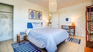 Une chambre à coucher avec un lit, un bureau et une chaise. Deux tableaux encadrés sont accrochés au mur.