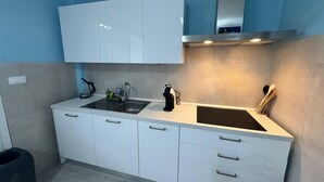 A modern kitchen with white cabinets, a stainless steel sink, and a range hood.