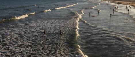 A beach with waves, people, and a distant shoreline.