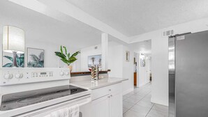 A modern kitchen with white cabinetry, a stainless steel refrigerator, and a built-in oven. - Walk to Beach - 2BR Between River & Ocean (Cocoa Beach)