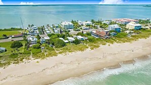 An aerial view of a coastal area with buildings, a beach, and the ocean. - Walk to Beach - 2BR Between River & Ocean (Cocoa Beach)