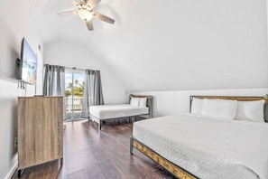 Une chambre avec un grand lit, un lit plus petit, une armoire en bois, un ventilateur de plafond et un téléviseur.