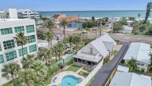 Área residencial com piscina, um edifício grande de telhado plano e vista para o oceano.