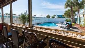 Uma área externa coberta com piscina, espreguiçadeiras e um deck de madeira.